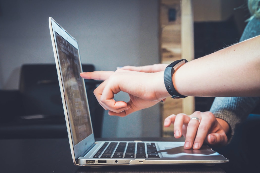 Une personne montre un contenu sur l'écran d'un ordinateur portable